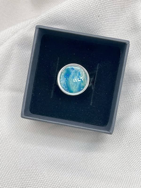 Anillo Mareas hecho a mano en tonos azules y blancos sobre fondo de tela